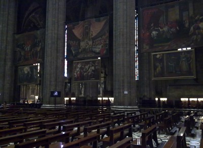 Langs de zijkanten van het middenschip hangen allemaal grote schilderijen